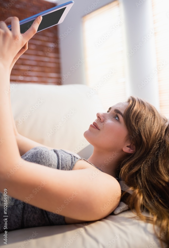 Pretty woman lying on the couch using her tablet Pretty woman lying on the couch using her tablet