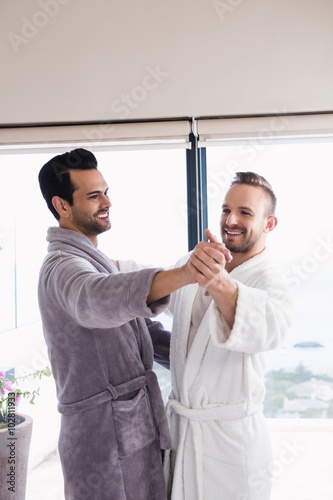 Happy gay couple dancing waltz in bathrobe