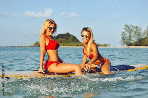 Surfer girls having fun on a surfboard in the sea
