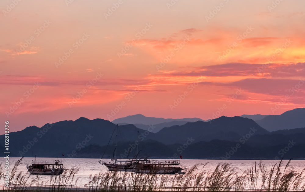 Sunset over the sea bay with mountains in the background.