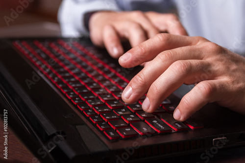 Laptop keyboard with fingers of a working man.