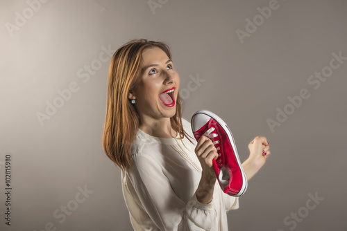 Foto Cheerful attractive teen girl sing song holding a red shoe like a microphone hol