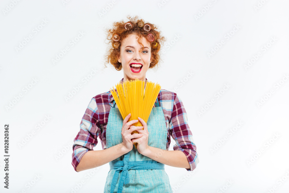 Happy housewife standing and holding uncooked spagetti Happy housewife standing and holding uncooked spagetti