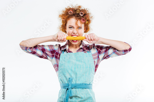 Attractive housewife holding and biting uncooked spagetti photo