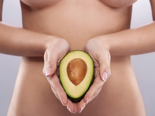 Naked woman holding the fresh avocado