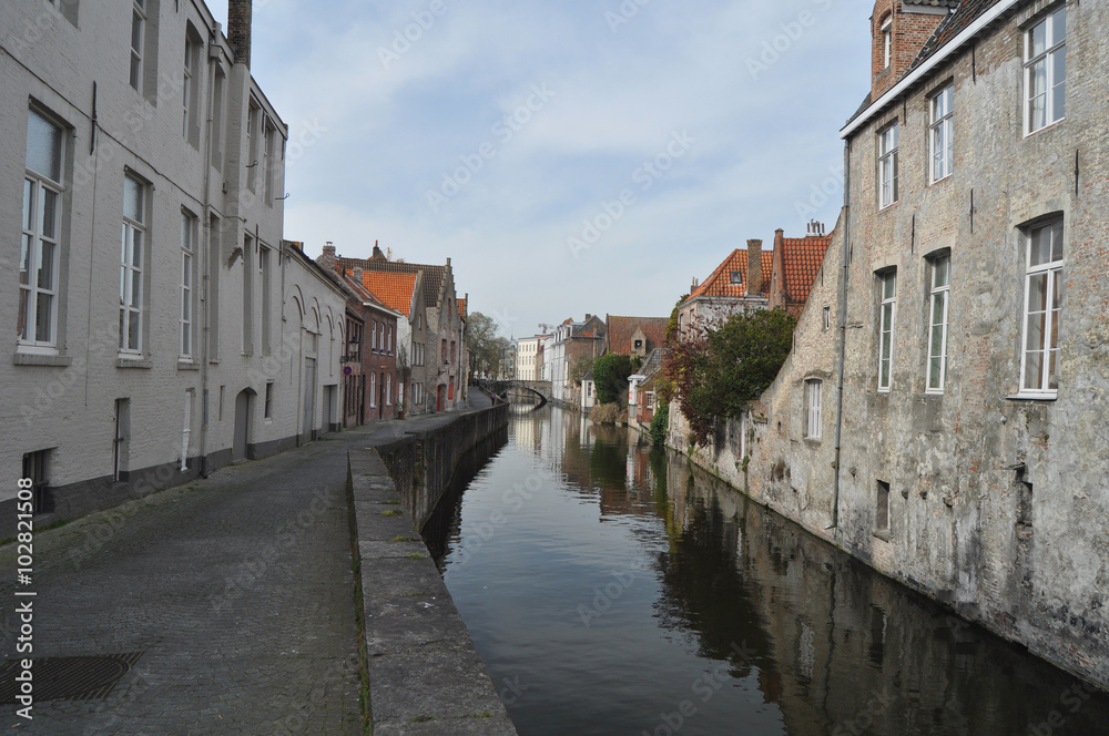 View of a typical canal flanked by traditional old buildings in charming Bruges Belgium.