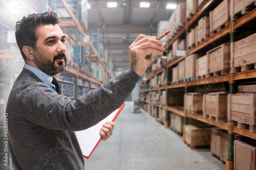 Young businessman checking inventory in a large warehouse