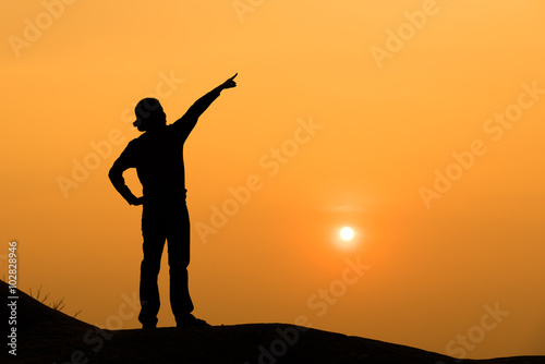 Silhouette of a woman point her hand to the sky