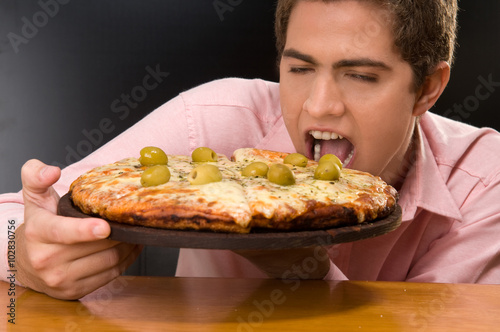 Excited young man eating pizza