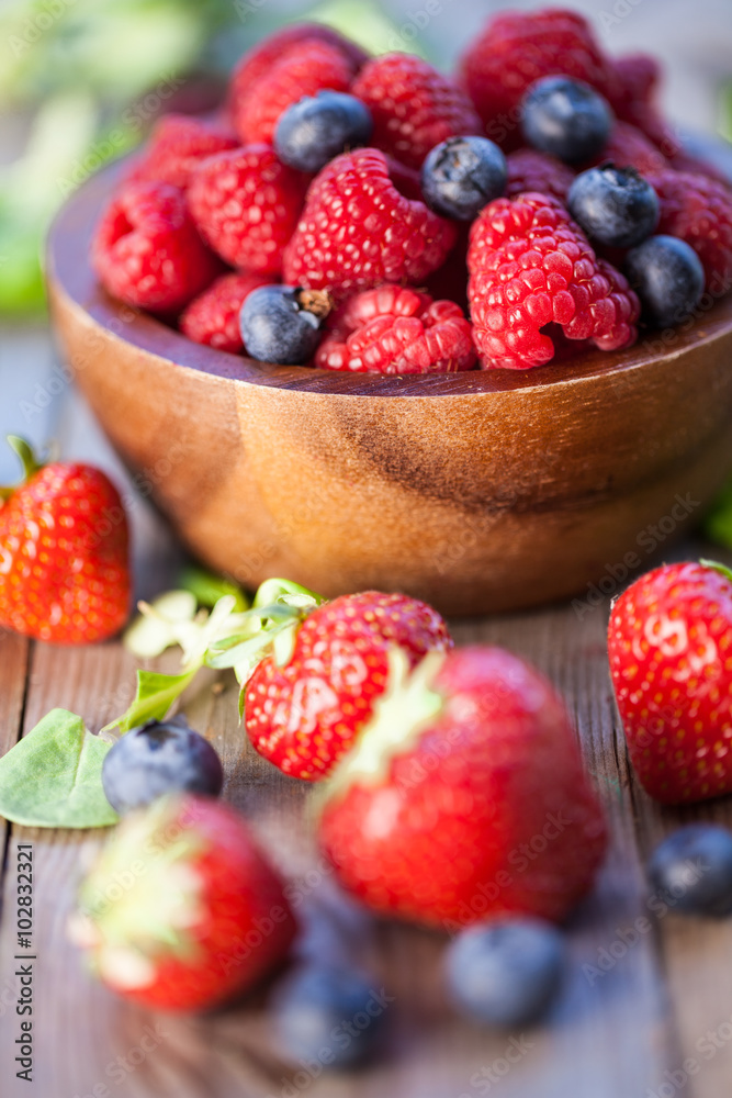 Raspberries, strawberry and blueberry on a wooden board. Natural background. Selective focus. Raspberries, strawberry and blueberry on a wooden board. Natural background. Selective focus.