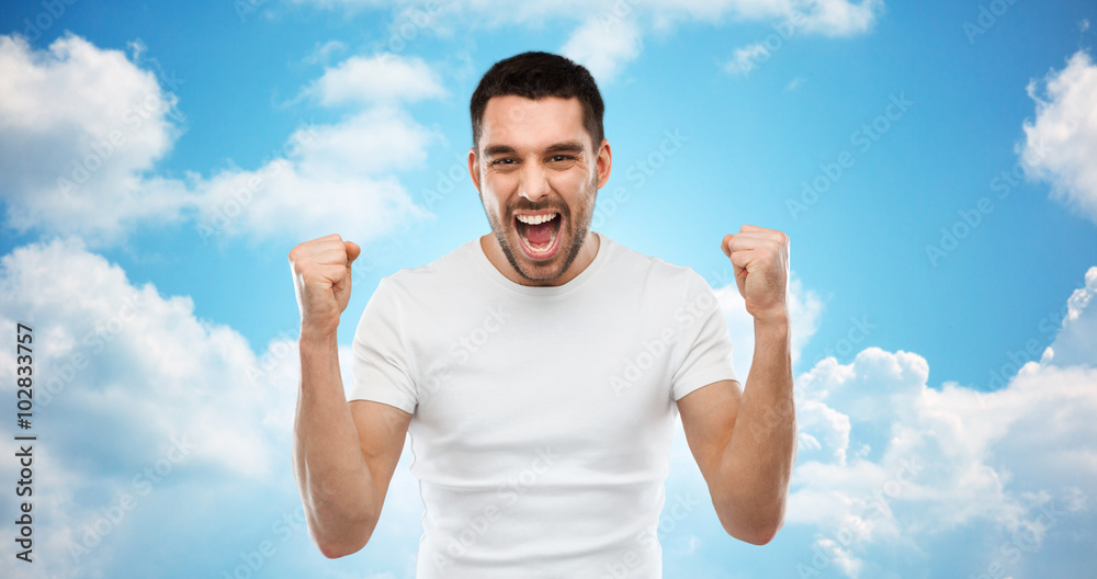 young man celebrating victory over blue sky young man celebrating victory over blue sky
