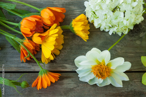 Yellow, orange and white flowers on gray old wooden table