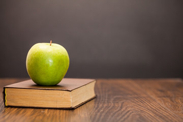 apple and book on wooden table