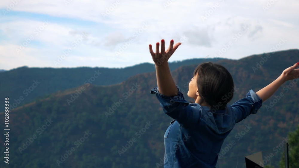 Young woman stretching her arms in the mountains, super slow motion 
