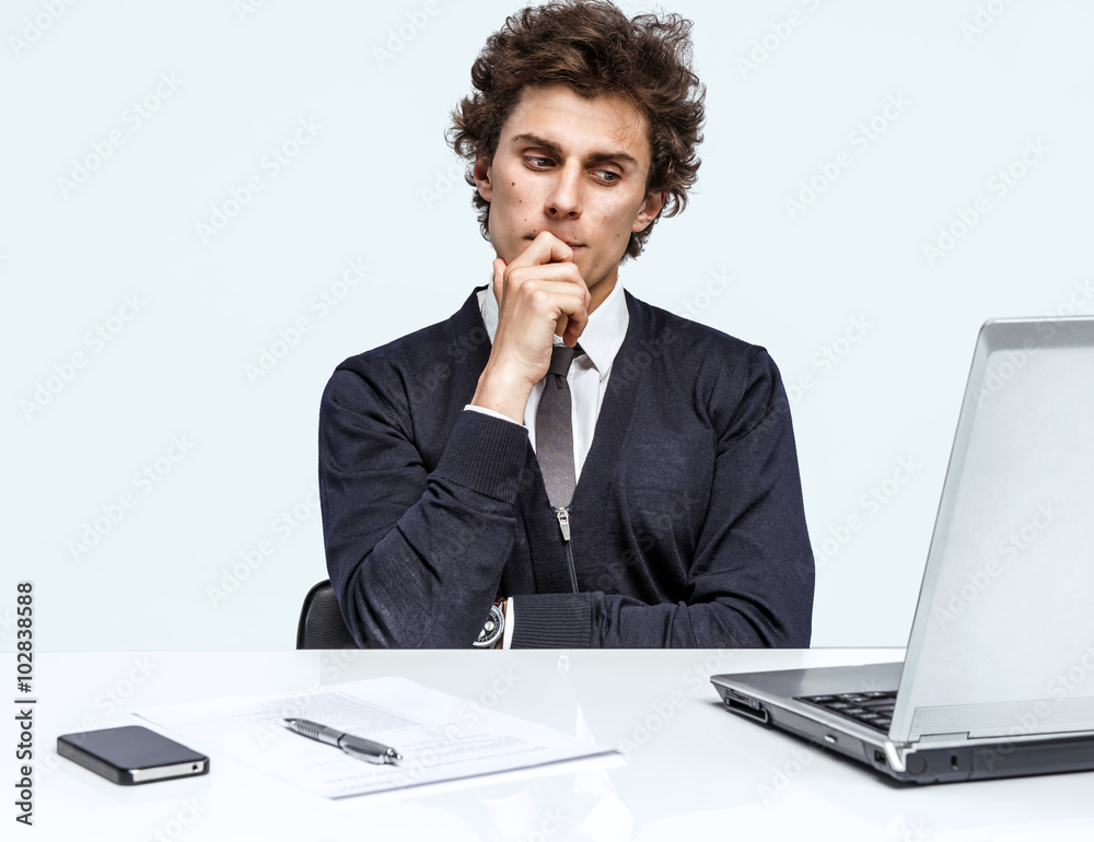 Doubter Businessman sitting in his office as he reads information or looks at a presentation on his computer on grey background. Depression and crisis concept Doubter Businessman sitting in his office as he reads information or looks at a presentation on his computer on grey background. Depression and crisis concept