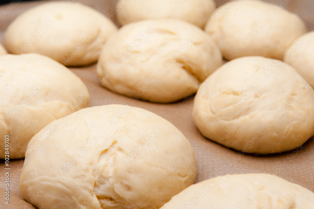 rohe selbstgemachte Teiglinge für Brioche/Hamburgerbrötchen auf einem Backblech mit Backpapier rohe selbstgemachte Teiglinge für Brioche/Hamburgerbrötchen auf einem Backblech mit Backpapier