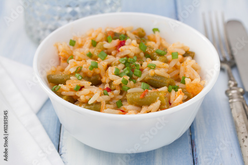 rice with vegetables in white bowl and glass of water