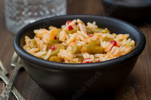 rice with vegetables in black bowl on brown wooden background