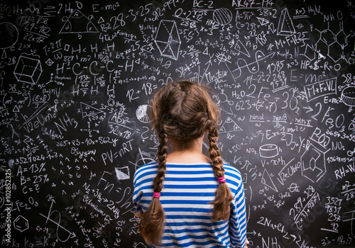 Girl against big blackboard with formulas, back view