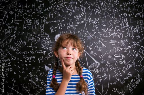 Girl  thinking, finger on cheek, blackboard with mathematical sy