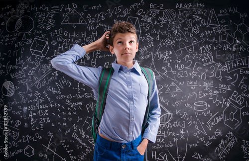 Boy thinking, scratching his head, blackboard with mathematical