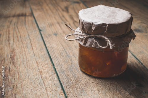 Jar with orange jam on wodden background