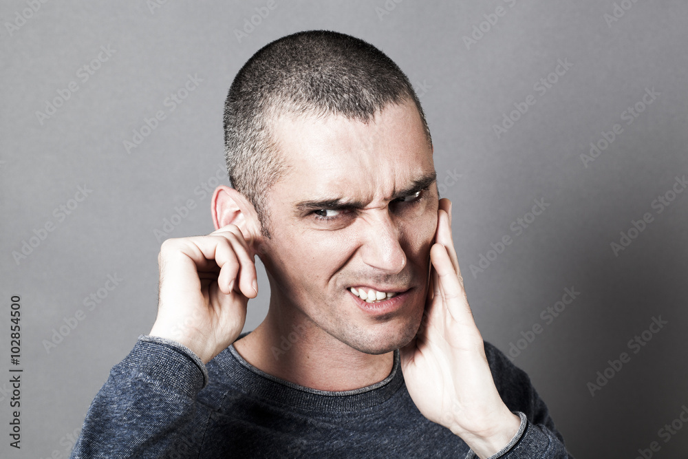 noise and hearing concept - nervous young man suffering from toothache or earache, touching his face for pain, contrast effects noise and hearing concept - nervous young man suffering from toothache or earache, touching his face for pain, contrast effects