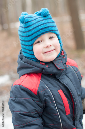 Small boy smiling on a walk in a winter park