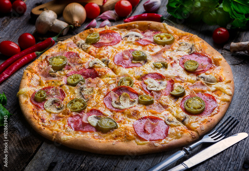 Pepperoni pizza with ham and jalapeno chili peppers