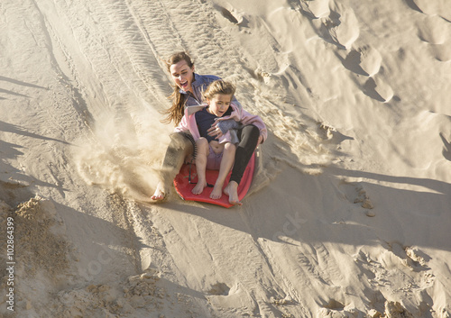 Fotografi Adventuresome girls boarding down the Sand Dunes