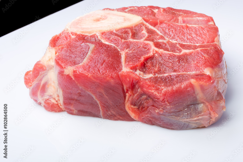one piece of raw beef meat with the bone in the middle on a white background one piece of raw beef meat with the bone in the middle on a white background