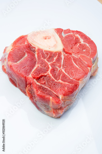 one piece of raw beef meat with the bone in the middle on a white background