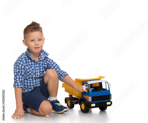 Fashion little boy in blue plaid shirt and shorts is sitting on the couch - Isolated on white background