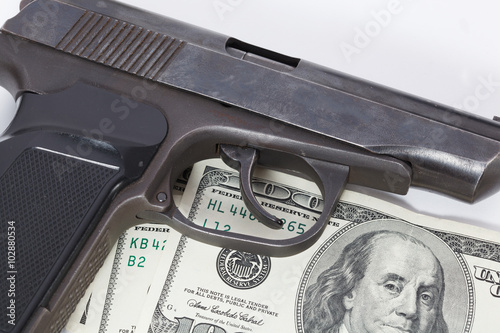 Black gun is lying on dollar bills