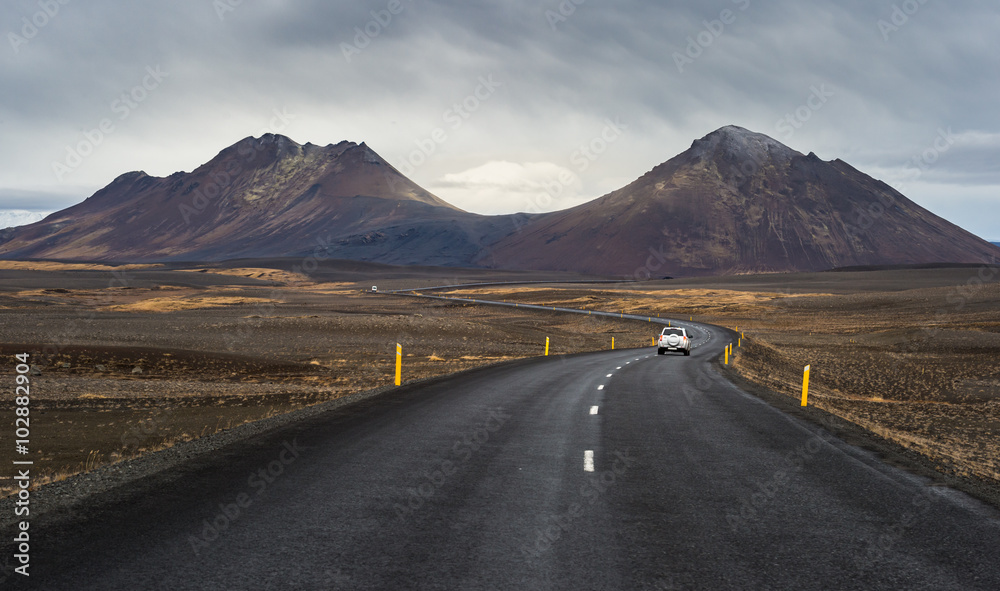 Dark asphalt road perspective with yellow field hill and mountain range background in Autumn season Iceland Dark asphalt road perspective with yellow field hill and mountain range background in Autumn season Iceland
