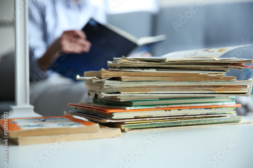 Pile of old books on white table in the room. Focus on books and blurred background