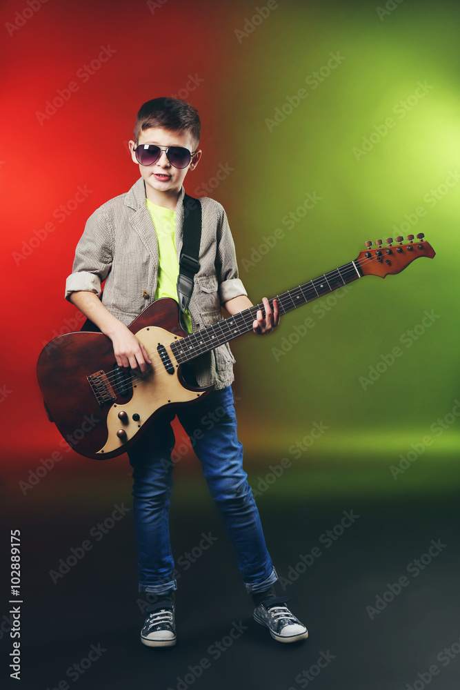 Obraz premium Little boy playing guitar on a bright background