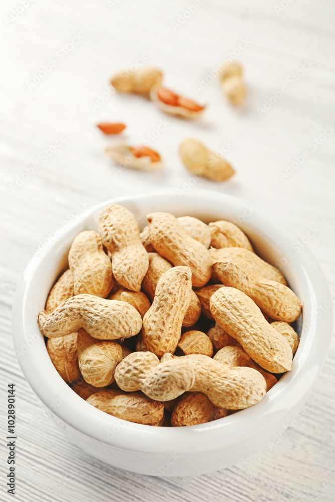 Peanuts in the bowl on white wooden background Peanuts in the bowl on white wooden background