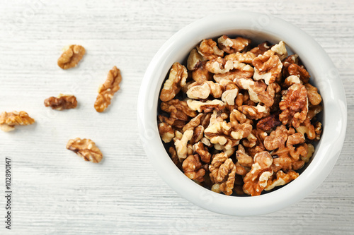 Walnut kernels in the bowl on white wooden background