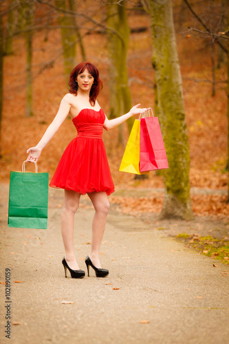autumn shopper woman with sale bags outdoor in park