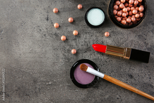 Makeup brush and cosmetics on grey background