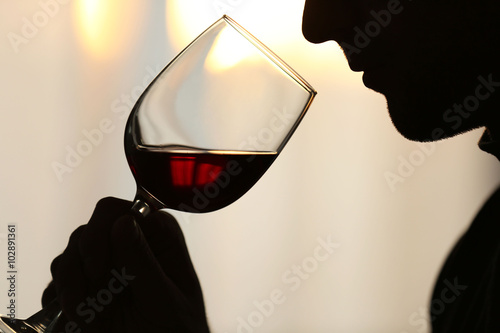 Fotografija Silhouette of man sniffing red wine in a glass, close up