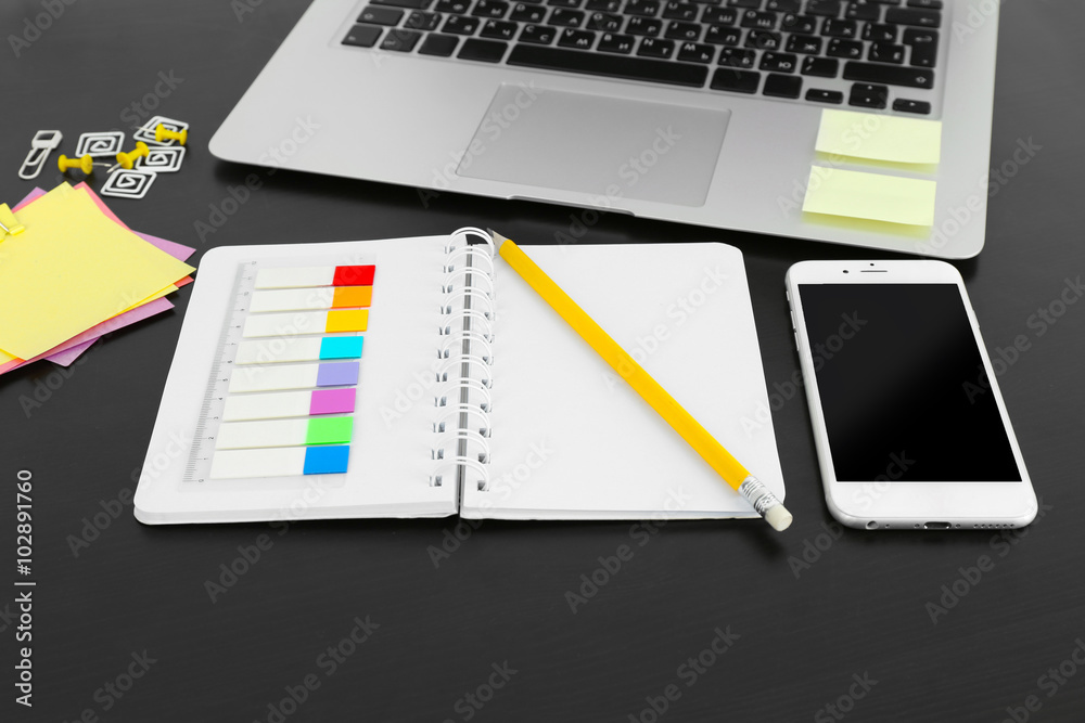 Workplace with mobile phone, laptop and stationery on black table Workplace with mobile phone, laptop and stationery on black table
