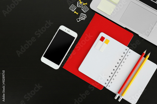 Workplace with mobile phone, laptop and stationery on black table