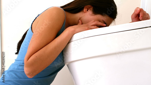 Rear view of woman throwing up in toilet photo