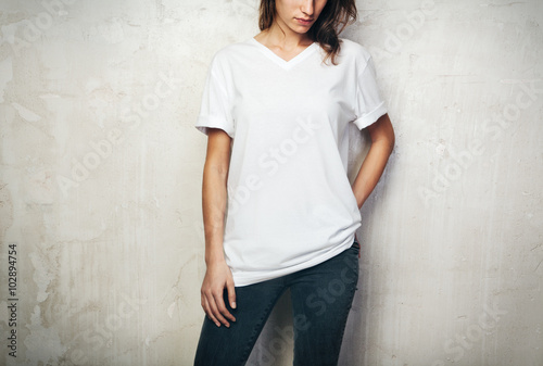 Young girl wearing blank t-shirt and black jeans. Concrete wall background