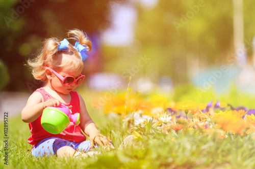 cute little girl watering flowers in summer