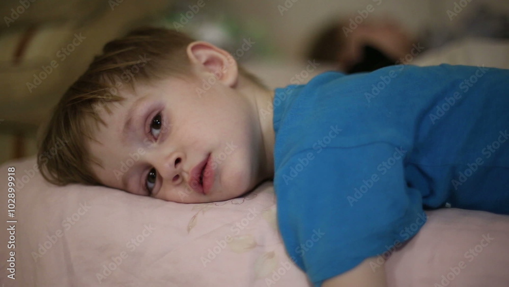 Little boy falls asleep, his eyelids heavy and eyes closed
Little boy falls asleep, his eyelids heavy and eyes closed