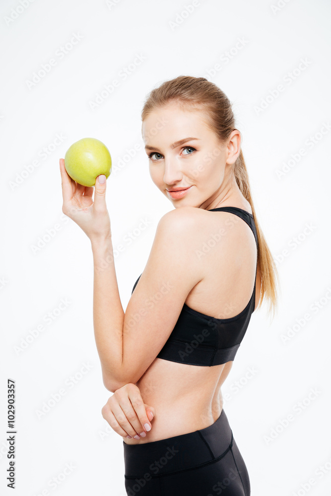 Charming woman athlete standing and posing with apple Charming woman athlete standing and posing with apple