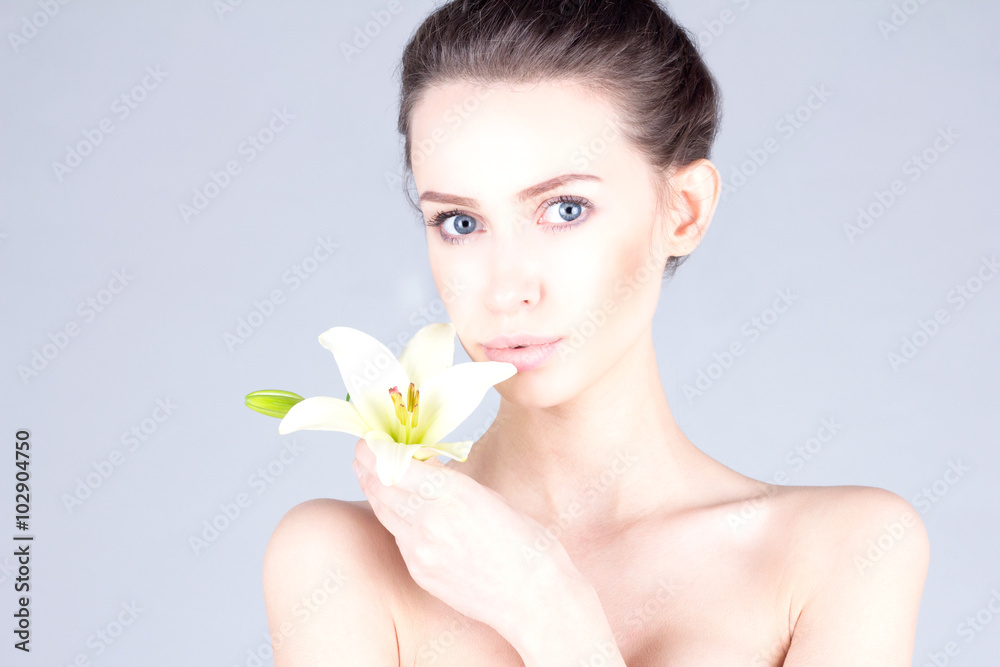 Beautiful young woman with a lily in her hands and with big blue eyes. SPA and beauty. Beautiful young woman with a lily in her hands and with big blue eyes. SPA and beauty.